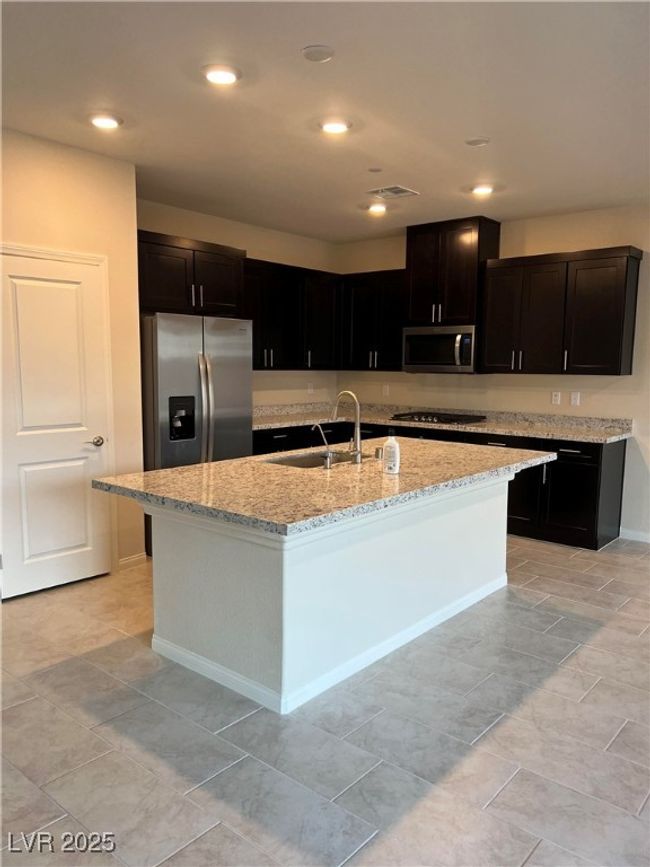 Kitchen with stainless steel appliances, a sink, light stone countertops, an island with sink, and recessed lighting | Image 8