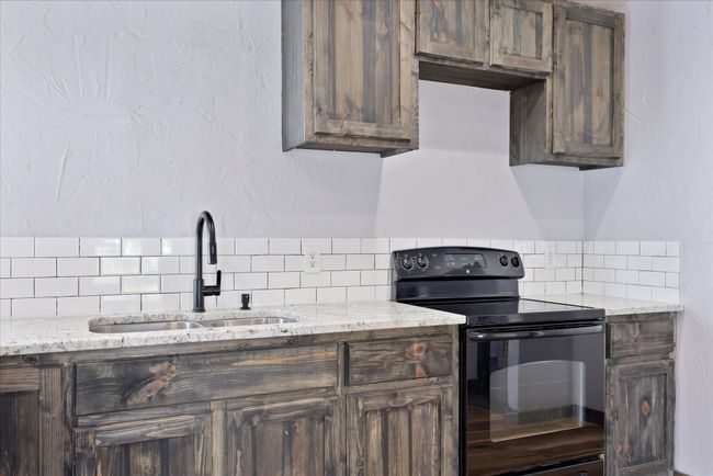 Kitchen with dark brown cabinetry, black electric range, and a sink | Image 16