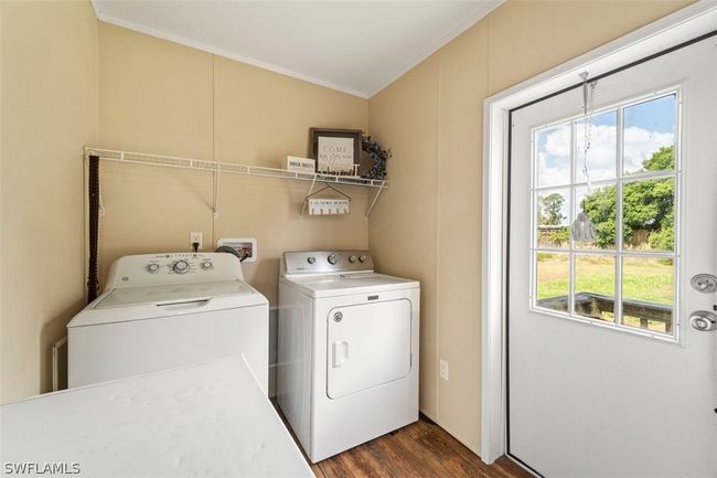 Laundry area with a healthy amount of sunlight, dark wood-type flooring, washer and clothes dryer, and washer hookup | Image 22