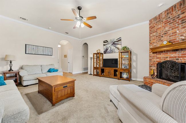 Living area featuring arched walkways, a ceiling fan, baseboards, crown molding, and light colored carpet | Image 9