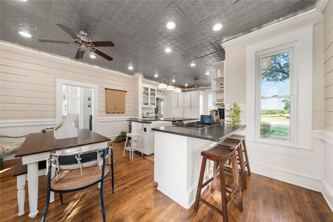 Kitchen featuring open shelves, dark wood-type flooring, dark countertops, white cabinets, and a peninsula | Image 9