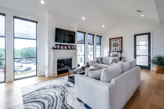 Another view of the living room with side door to the balcony, pretty contemporary wood floors, fire place, tastefully decorated. | Image 6