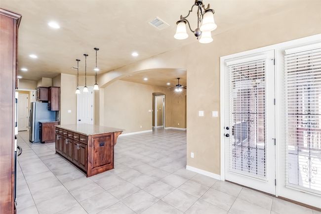 Kitchen with arched walkways, pendant lighting, visible vents, and freestanding refrigerator | Image 18