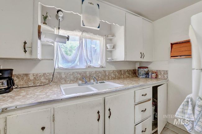 Kitchen with white cabinets, light countertops, and open shelves | Image 9