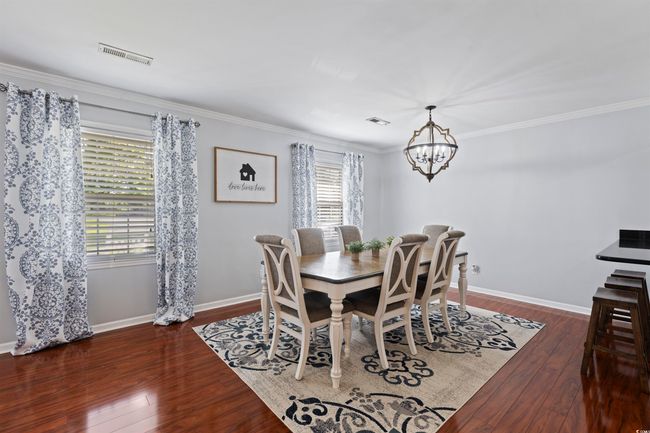 Dining area with a chandelier, hardwood / wood-style floors, ornamental molding, and baseboards | Image 4