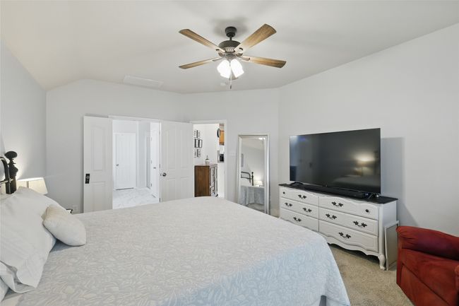 Bedroom with light colored carpet, vaulted ceiling, and ceiling fan | Image 25