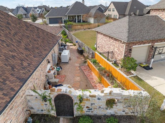 The Front Garden Wallconstructed of customblend natural stone with Old Chicago Brickaccents to match thaton the house and create an Old World "crumbling" look, reminiscent of those seen in the French or Italian countryside.Behind the wall, thespace was designed tobe a "working" gardenarea, with a customstone potting bench, raised beds, and astepping stone path tothe backyard pool area. | Image 43