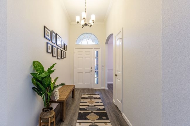 Entryway featuring ornamental molding, dark wood-style floors, a chandelier, arched walkways, and baseboards | Image 4