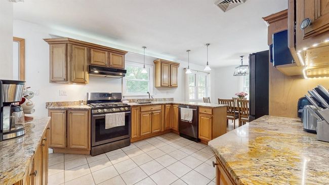 Fabulous Kitchen with stainless steel appliances, under cabinet range hood, a peninsula, lots of rich oak cabinets, pendant lighting, and granite counters. | Image 13