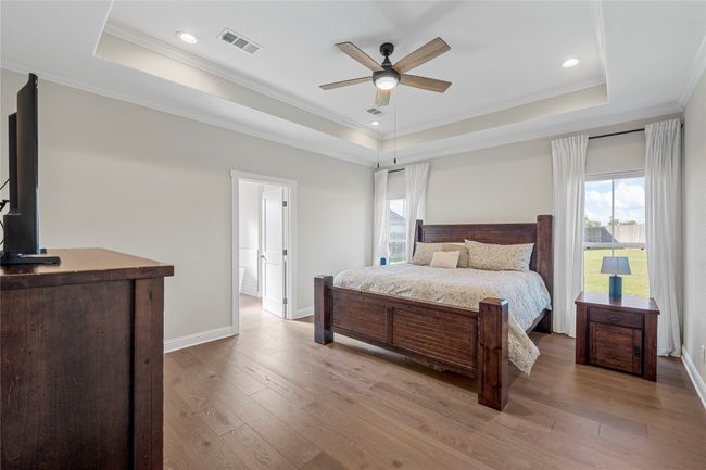 Bedroom with multiple windows, visible vents, a tray ceiling, and ornamental molding | Image 22