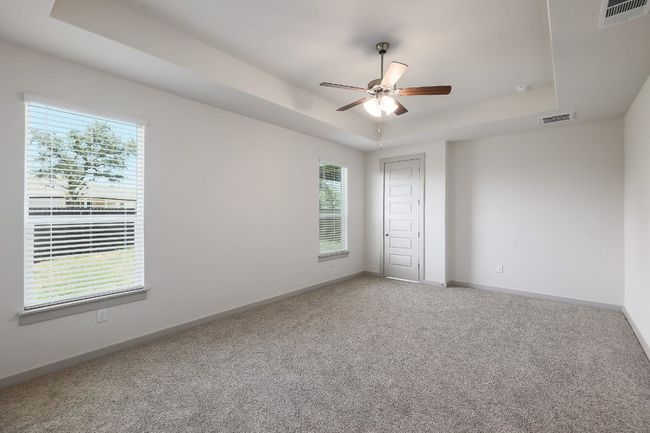 Carpeted bedroom with a tray ceiling and ceiling fan | Image 13