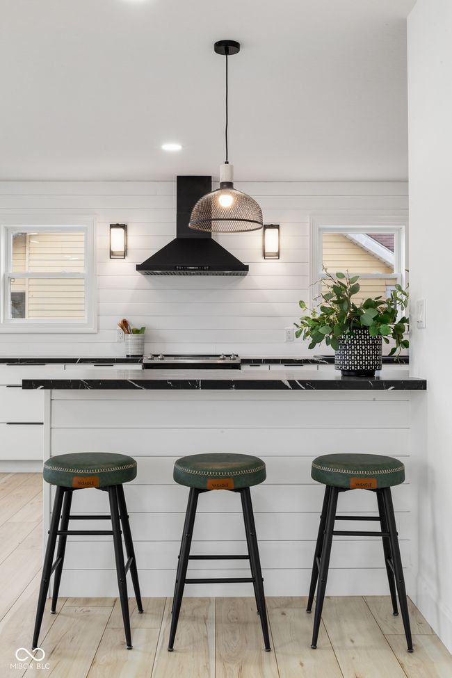 kitchen featuring wall chimney range hood, a kitchen breakfast bar, and dark countertops | Image 20