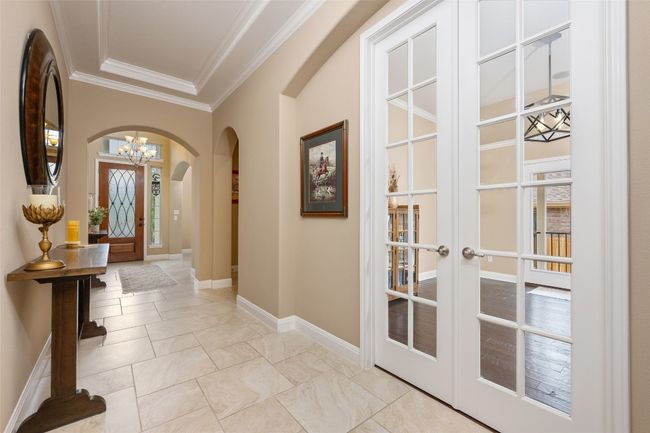 Entryway featuring arched walkways, ornamental molding, a chandelier, and french doors | Image 10
