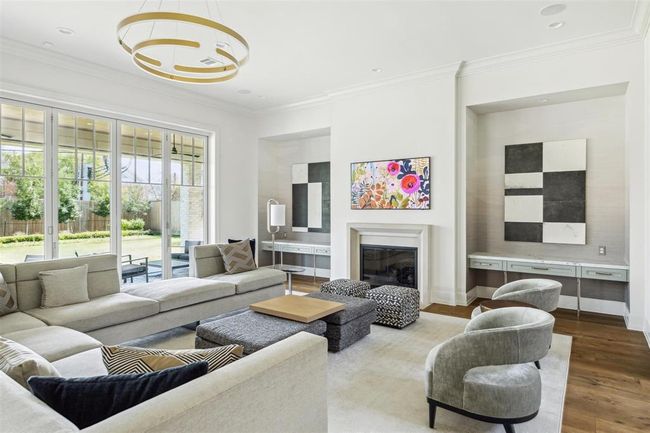 Bathed in natural light, the family room offers refined comfort, centered around a gas log fireplace with a cast stone surround and elegant white oak hardwoods. Expansive sliding glass doors seamlessly connect the space to the stunning outdoor living area. | Image 7