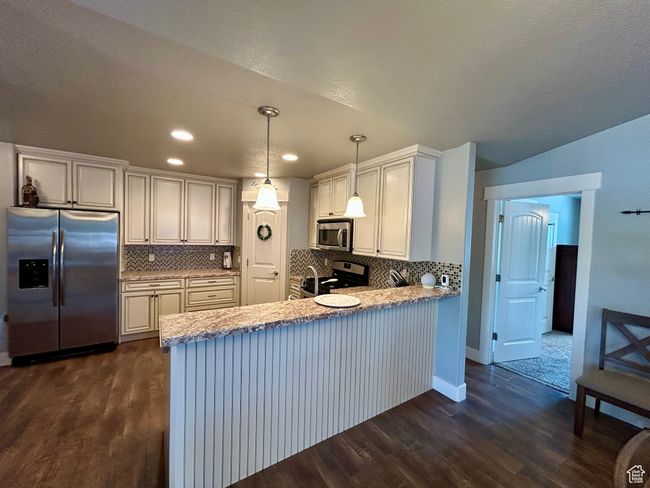 Kitchen with stainless steel appliances, dark wood-style flooring, a peninsula, tasteful backsplash, and recessed lighting | Image 12