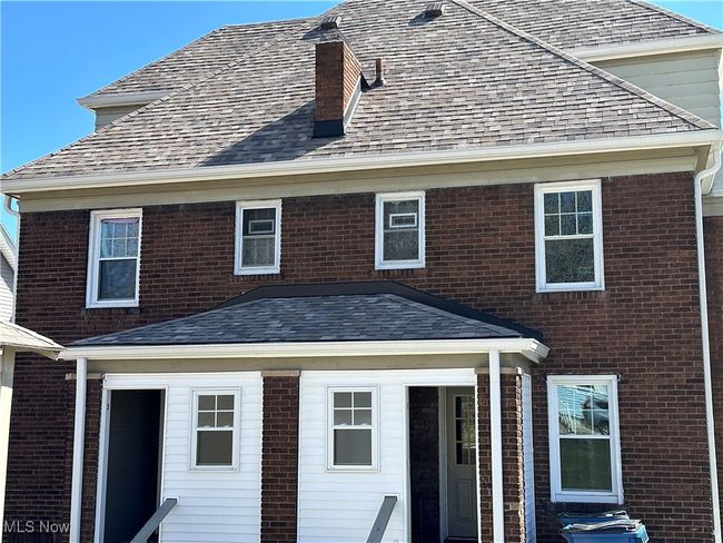 Rear view of property featuring a shingled roof, brick siding, and a chimney | Image 4