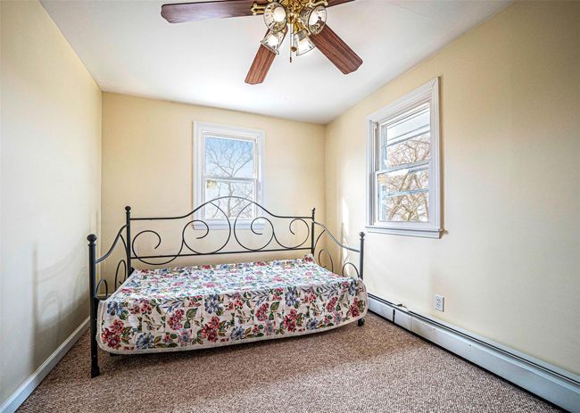 Bedroom featuring carpet flooring, a baseboard radiator, and ceiling fan | Image 12