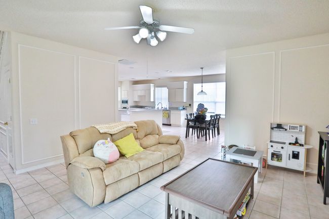 Living room featuring a ceiling fan and light tile patterned flooring | Image 10