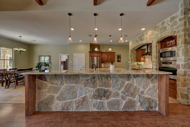 This kitchen features a stunning bar with elegant pendant lighting, ideal for entertaining and casual dining. | Image 9
