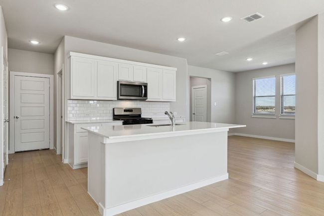Kitchen with stainless steel appliances, a sink, tasteful backsplash, light wood-type flooring, and light countertops | Image 4