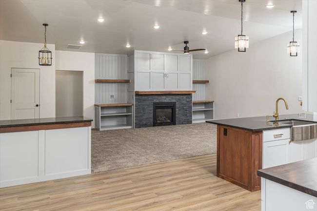 Kitchen with ceiling fan, sink, pendant lighting, a fireplace, and white cabinets | Image 12