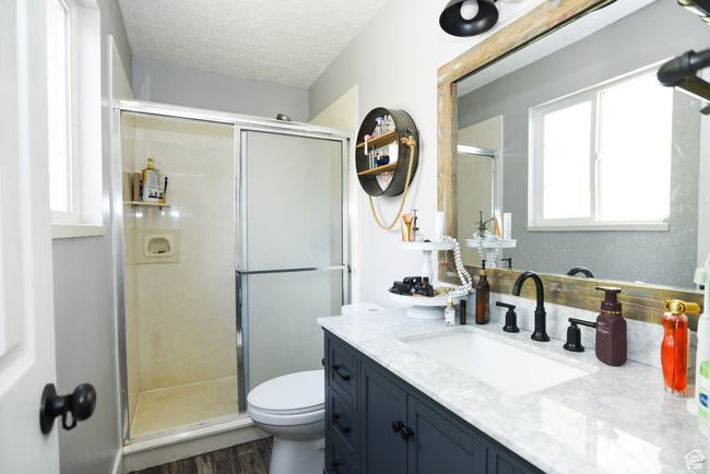 Bathroom featuring wood finished floors, a shower stall, toilet, vanity, and a textured ceiling | Image 25