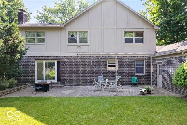 rear view of property with a chimney, a yard, brick siding, board and batten siding, and a patio | Image 35