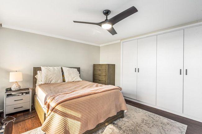 Bedroom with ornamental molding, dark wood finished floors, a closet, and a ceiling fan | Image 5