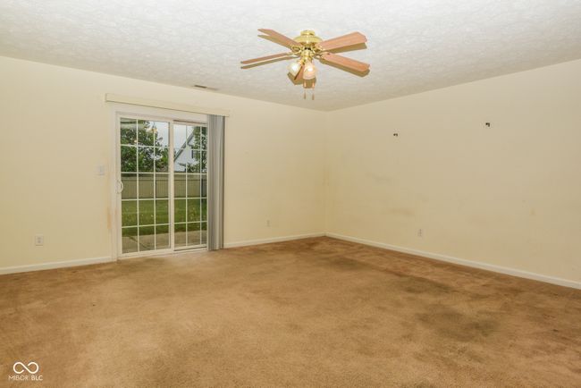 spare room featuring a textured ceiling, light colored carpet, baseboards, and ceiling fan | Image 6