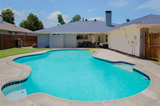 View of swimming pool featuring a fenced backyard, a ceiling fan, and a patio | Image 4