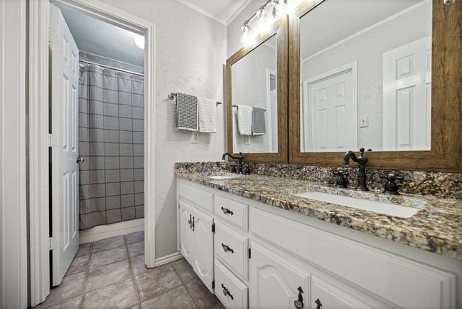 Full bathroom with stone finish flooring, double vanity, a sink, and ornamental molding | Image 21