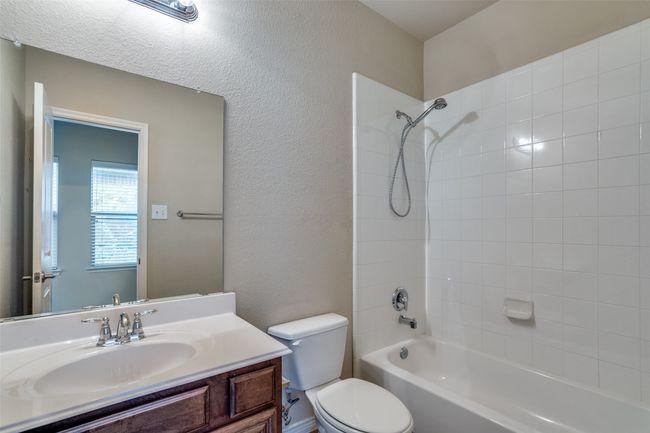 Full bathroom featuring a textured wall, bathtub / shower combination, vanity, and toilet | Image 21
