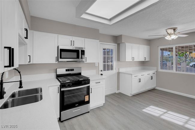Kitchen with stainless steel appliances, light countertops, a ceiling fan, a sink, and light wood-style flooring | Image 16