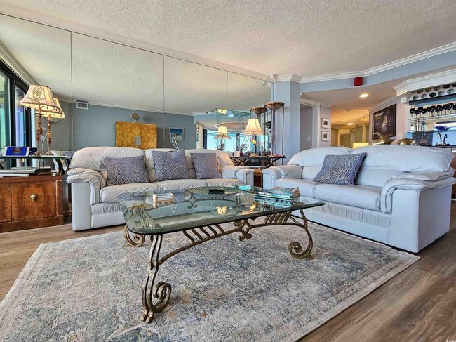 Living area featuring a textured ceiling, ornamental molding, wood finished floors, and visible vents | Image 7