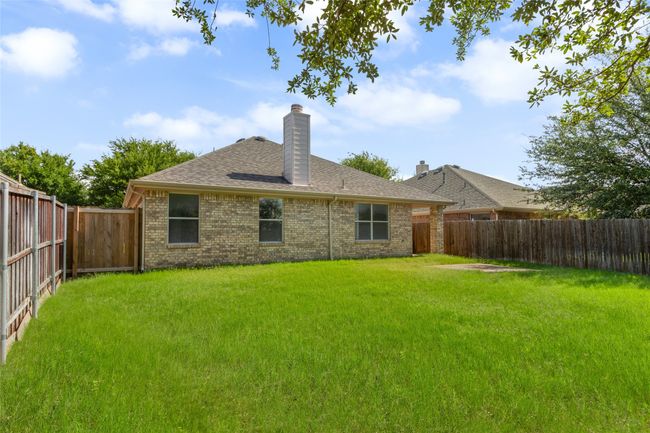 Back of property featuring a fenced backyard, brick siding, a chimney, and a shingled roof | Image 25