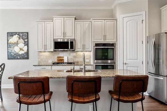 Kitchen with a kitchen breakfast bar, appliances with stainless steel finishes, decorative backsplash, and a sink | Image 10
