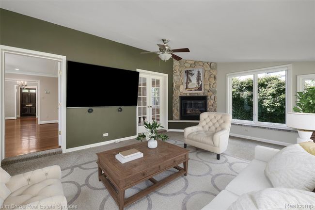 Carpeted living area with a ceiling fan, ornamental molding, and a stone fireplace | Image 6