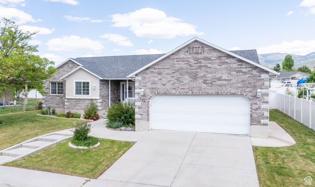 Ranch-style house with an attached garage, concrete driveway, brick siding, and a mountain view | Image 5