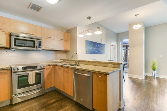 Kitchen with visible vents, dark wood-type flooring, a sink, stainless steel appliances, and a peninsula | Image 7