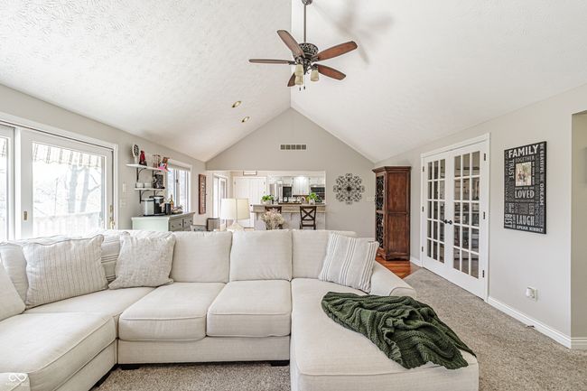 carpeted living room with visible vents, lofted ceiling, baseboards, and ceiling fan | Image 7