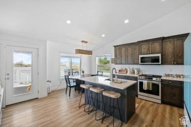 Kitchen featuring a sink, a breakfast bar, dark brown cabinetry, light countertops, and gas stove | Image 12