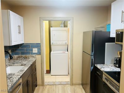 Kitchen featuring appliances , newer cabinetry, and stacked washer / dryer | Image 3