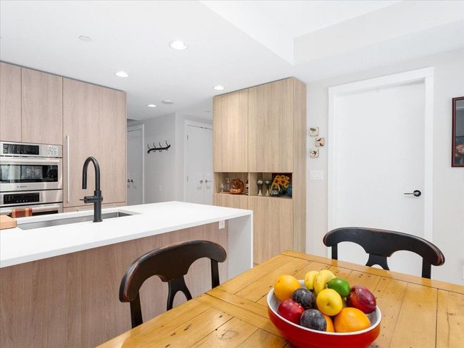 Kitchen featuring modern cabinets, a sink, double oven, a kitchen breakfast bar, and light countertops | Image 9