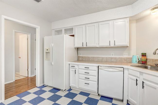 Kitchen featuring white appliances, a sink, light flooring, white cabinets, and light countertops | Image 9
