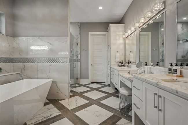 A spacious, elegantly designed bathroom featuring a standalone tub, unique fixtures, an oversized shower, dual sinks, and vanity. | Image 28