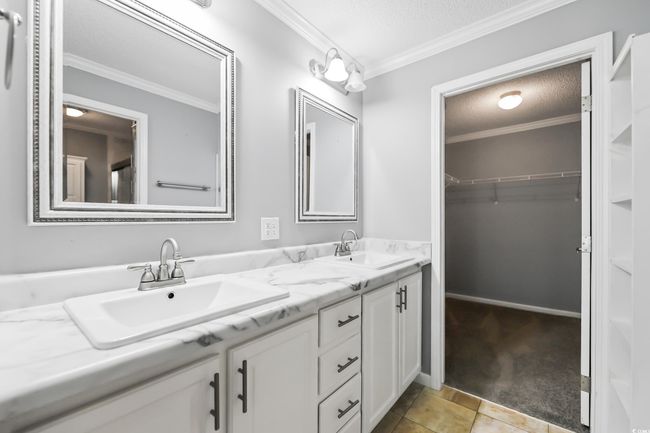 Full bathroom featuring a textured ceiling, double vanity, ornamental molding, a spacious closet, and tile patterned floors | Image 21