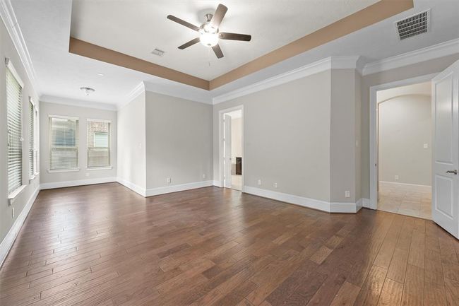 This primary suite is massive—you’ve got space for a king bed plus a bonus sitting nook under the tray ceiling. Rich hardwood floors flow throughout, and three large windows flood the room with natural light and frame peaceful backyard views. It’s a private retreat perfect for morning coffee, reading, or just unwinding at the end of the day. | Image 14