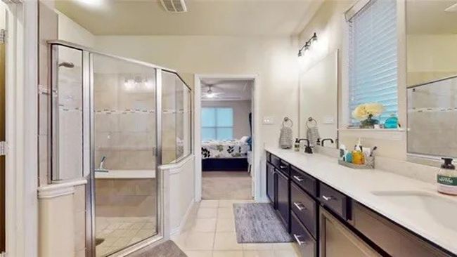 Full bath featuring double vanity, a shower stall, light tile patterned floors, and ensuite bath | Image 6