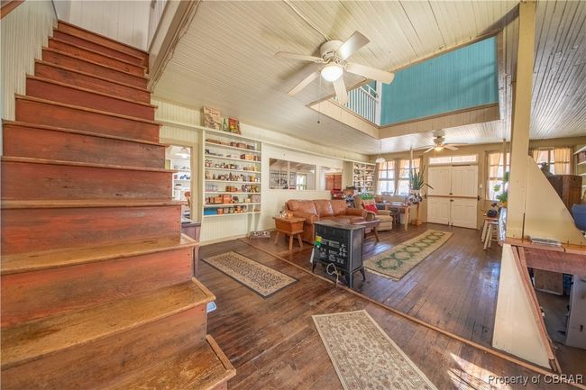 Living room with stairway, a ceiling fan, and wood-type flooring | Image 25
