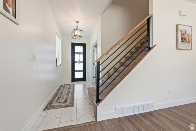 Entrance foyer with baseboards, visible vents, an inviting chandelier, marble finish floor, and stairway | Image 11